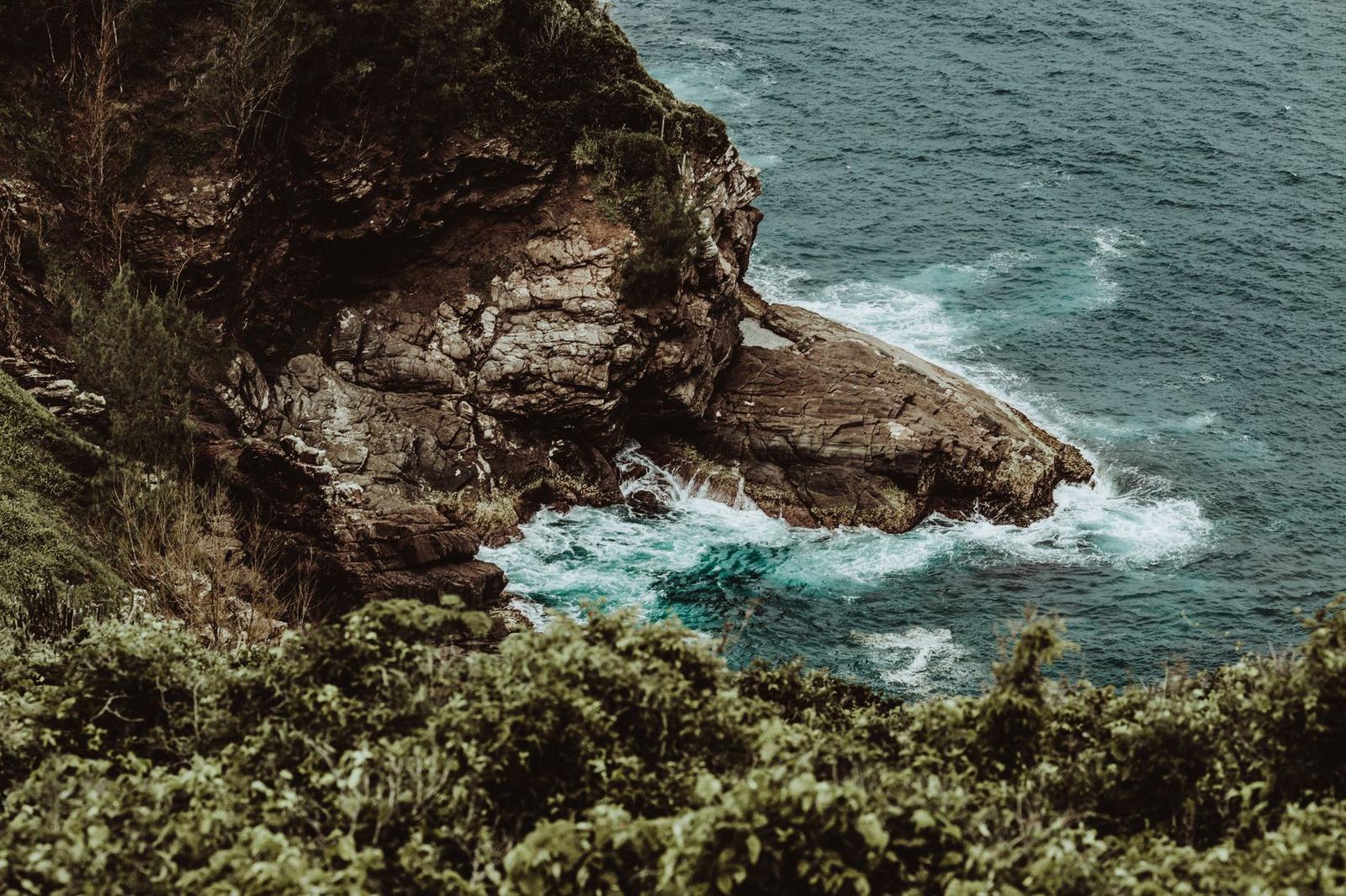 Foamy Waves of Sea Splashing on Rocky Coast with Rough Formations